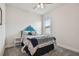 Bedroom featuring gray carpet, a window, and a bed with a unique blue headboard and patterned bedding at 8192 Ivy Stark Blvd, Wesley Chapel, FL 33545