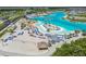 Aerial view of a community beach area with volleyball court, lounge chairs, thatched umbrellas and palm trees at 8192 Ivy Stark Blvd, Wesley Chapel, FL 33545