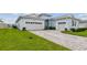 A paved driveway leading to a light blue single-Gathering home, showcasing its attached two-car garage at 8192 Ivy Stark Blvd, Wesley Chapel, FL 33545