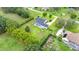 Aerial view of backyard with screened pool and large, green lawn with some trees and a garden at 9830 Caribou Trl, Dade City, FL 33525