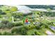 An aerial view of home in a residential neighborhood surrounded by lush greenery and a lake at 9830 Caribou Trl, Dade City, FL 33525