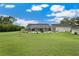 Backyard featuring a well-maintained lawn, mature trees and screened lanai with pool at 9830 Caribou Trl, Dade City, FL 33525