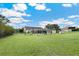 View of the spacious and well-manicured backyard, with screened lanai and fire pit at 9830 Caribou Trl, Dade City, FL 33525