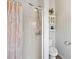 Bathroom featuring a shower with a peach-colored curtain, toilet, and small storage unit with an eye-catching plant at 9830 Caribou Trl, Dade City, FL 33525