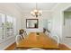 Spacious dining room with a wooden table, shuttered windows, and modern chandelier at 9830 Caribou Trl, Dade City, FL 33525