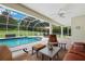Inviting screened-in patio featuring cozy furniture, a ceiling fan, and access to the sparkling pool at 9830 Caribou Trl, Dade City, FL 33525