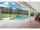 Screened-in pool featuring brick and concrete surround with a large grassy yard at 9830 Caribou Trl, Dade City, FL 33525