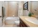 Well-maintained bathroom featuring tile floors and walls, a tub with shower, and a wood vanity at 11314 American Holly Dr, Riverview, FL 33578