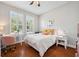 Bright bedroom features wood floors, a desk and chair, and large windows with plantation shutters at 11314 American Holly Dr, Riverview, FL 33578