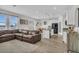 Open-concept living room featuring a large brown leather sofa and a modern kitchen with white cabinets at 11847 Brighton Knoll Loop, Riverview, FL 33579