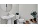 Cozy powder room features a pedestal sink, round mirror, and modern fixtures at 12650 Shetland Walk Dr, Lithia, FL 33547