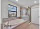 Luxurious bathroom with a soaking tub, glass-enclosed shower, and neutral tile surround at 12650 Shetland Walk Dr, Lithia, FL 33547
