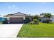 Inviting home featuring a lush green lawn, mature palm trees, and vibrant flower beds under a clear blue sky at 13168 84Th Ter, Seminole, FL 33776