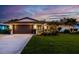 Charming home with a well-manicured lawn and tropical landscaping, illuminated by warm exterior lighting at 13168 84Th Ter, Seminole, FL 33776