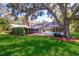 Home and pool from yard featuring a screened-in enclosure and mature trees at 1670 Fox Rd, Clearwater, FL 33764