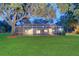 Expansive backyard featuring a screened-in pool enclosure, mature trees, and lush green lawn at 1670 Fox Rd, Clearwater, FL 33764