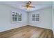 Bedroom featuring light walls, wood floors, ceiling fan and shuttered windows at 1670 Fox Rd, Clearwater, FL 33764