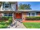 Charming brick home featuring a cozy front entrance with a red double door and landscaped garden at 1670 Fox Rd, Clearwater, FL 33764
