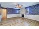 Spacious living room with beautiful wallpaper, ceiling fan, wood floors, and cozy fireplace at 1670 Fox Rd, Clearwater, FL 33764