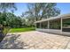 Backyard with brick patio, screened-in porch, and mature trees, creating a private outdoor space at 17801 Simmons Rd, Lutz, FL 33548