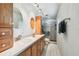 Well-lit bathroom featuring double sinks, wood cabinets, and a walk-in shower at 17801 Simmons Rd, Lutz, FL 33548