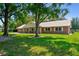 Beautiful single-story brick home featuring a metal roof, well-maintained lawn, and mature trees adding to the property's curb appeal at 17801 Simmons Rd, Lutz, FL 33548