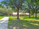 Inviting home with a metal roof, lush lawn, and mature trees; featuring a long driveway and a shed for additional storage at 17801 Simmons Rd, Lutz, FL 33548
