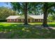 Inviting brick home showcases a durable metal roof, well-manicured lawn, and mature trees providing shade and enhancing curb appeal at 17801 Simmons Rd, Lutz, FL 33548