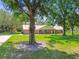 Charming home with a metal roof, lush lawn, and mature trees; featuring a long driveway leading to the residence at 17801 Simmons Rd, Lutz, FL 33548
