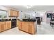 Kitchen featuring custom wood cabinets, black granite countertops, stainless steel appliances, an island, and white tile floors at 17801 Simmons Rd, Lutz, FL 33548