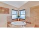 Bright bathroom featuring an oval soaking tub with travertine tile surround and two windows at 19412 Heritage Harbor, Lutz, FL 33558