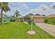 Well-maintained single-story home with a lush front lawn and beautiful tropical palm trees at 2316 Lyndhurst Dr, Sun City Center, FL 33573