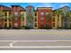 Striking multi-story building with vibrant colors, symmetrical balconies, and lush palm trees along a wide city street at 2410 W Azeele St # 214, Tampa, FL 33609