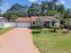Charming home featuring brick driveway, manicured lawn, mature trees, and an American flag at 2484 Whitman St, Clearwater, FL 33765