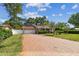 Wide view of the charming home with brick driveway, manicured lawn and lush landscaping at 2484 Whitman St, Clearwater, FL 33765