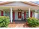 Inviting front porch with red shutters, red door, brick flooring and lush landscaping at 2484 Whitman St, Clearwater, FL 33765
