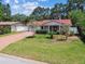Charming single-story home with a well-manicured lawn, mature trees, and a brick driveway leading to the garage at 2484 Whitman St, Clearwater, FL 33765