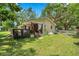 Backyard with wooden deck with curtains, new fencing, and mature trees at 316 Jenkins Ave, Brooksville, FL 34604