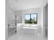 Bright bathroom with white freestanding tub, glass shower, and a large window with view at 3344 Lagoy St, North Port, FL 34291