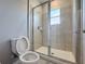 Bathroom featuring glass shower enclosure, tiled walls, and a toilet with a window view at 34187 Rogallo Ln, Wesley Chapel, FL 33545