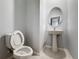 Powder room featuring a sleek pedestal sink, modern mirror, and tile flooring; simple, stylish design at 34187 Rogallo Ln, Wesley Chapel, FL 33545