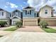 View of charming two-story townhomes with colorful facades, well-manicured lawns, and brick driveways on a sunny day at 34187 Rogallo Ln, Wesley Chapel, FL 33545
