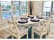 Cozy dining area with an oval table, seating for six, and scenic water views through the shuttered windows at 4103 Gulf Blvd # 210, St Pete Beach, FL 33706
