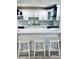 Eat-in kitchen with breakfast bar, stylish barstools, white cabinets, white countertops, and backsplash at 4103 Gulf Blvd # 210, St Pete Beach, FL 33706