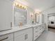 Updated bathroom features double vanity with white cabinets, granite counters, and modern gold fixtures and lighting at 4710 W Tambay Ave, Tampa, FL 33611