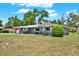 Charming single-story home with lush lawn, mature trees, and a driveway leading to an attached garage at 5068 Lakewood Dr, Ridge Manor, FL 33523