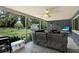 Screened porch with seating, mounted television, outdoor cooking area and backyard view at 5068 Lakewood Dr, Ridge Manor, FL 33523