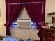 Bedroom with an air conditioning unit in the window, covered by heavy burgundy curtains at 5279 Eureka Springs Rd, Tampa, FL 33610