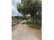 Gravel driveway leading up to a residence with green trees and grass on either side, fenced at 5279 Eureka Springs Rd, Tampa, FL 33610