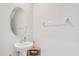 White powder room with oval mirror, pedestal sink, and a convenient towel bar at 7211 Ronnie Gardens Ct, Tampa, FL 33619